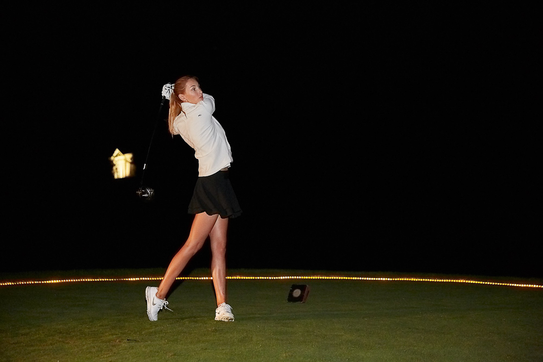 Woman golfing at night with light on her