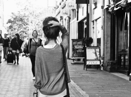 Female holding up her hair as she walks highlighting her slim neck.