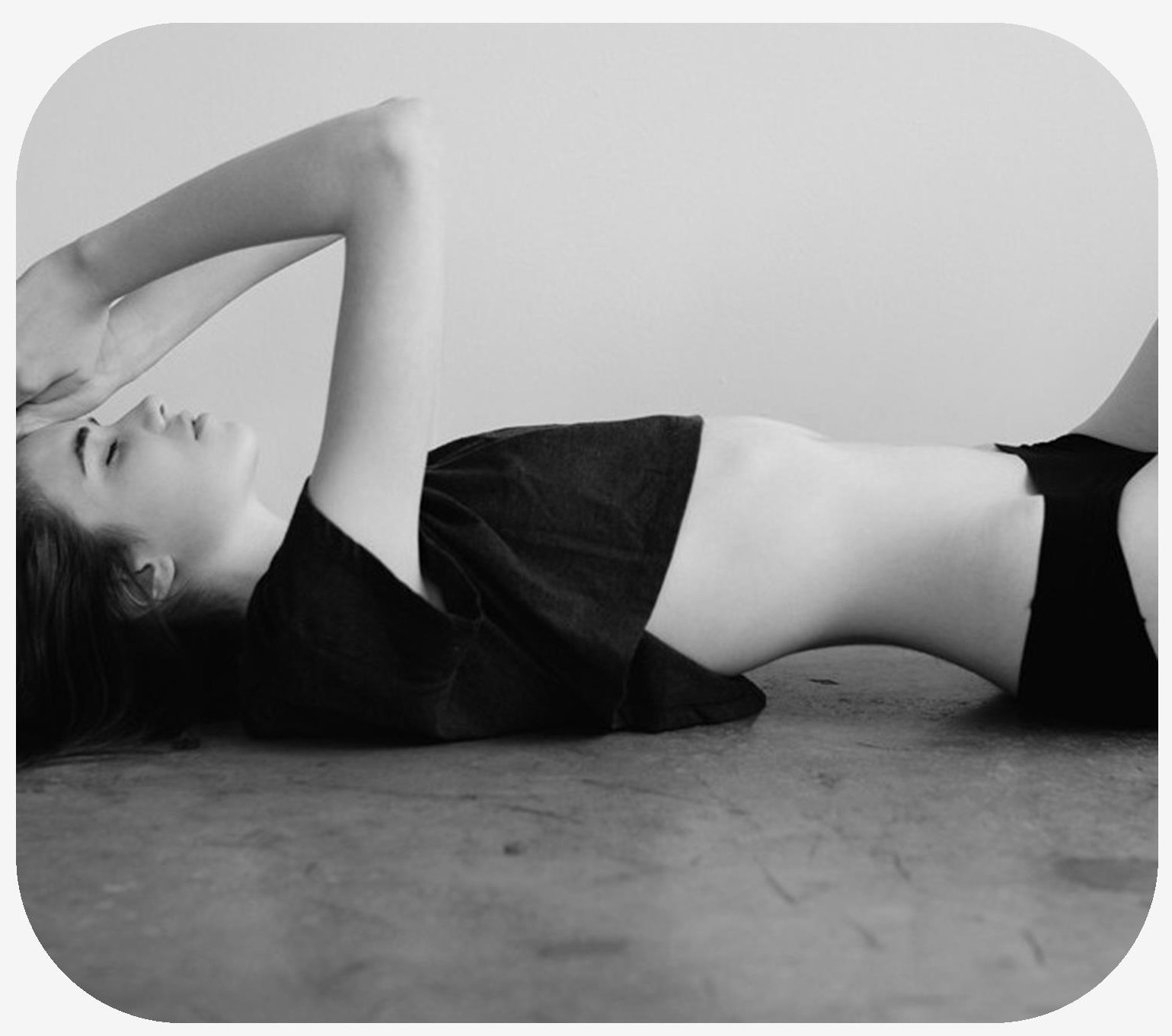 Woman laying on the floor with back arched and skin exposed on belly