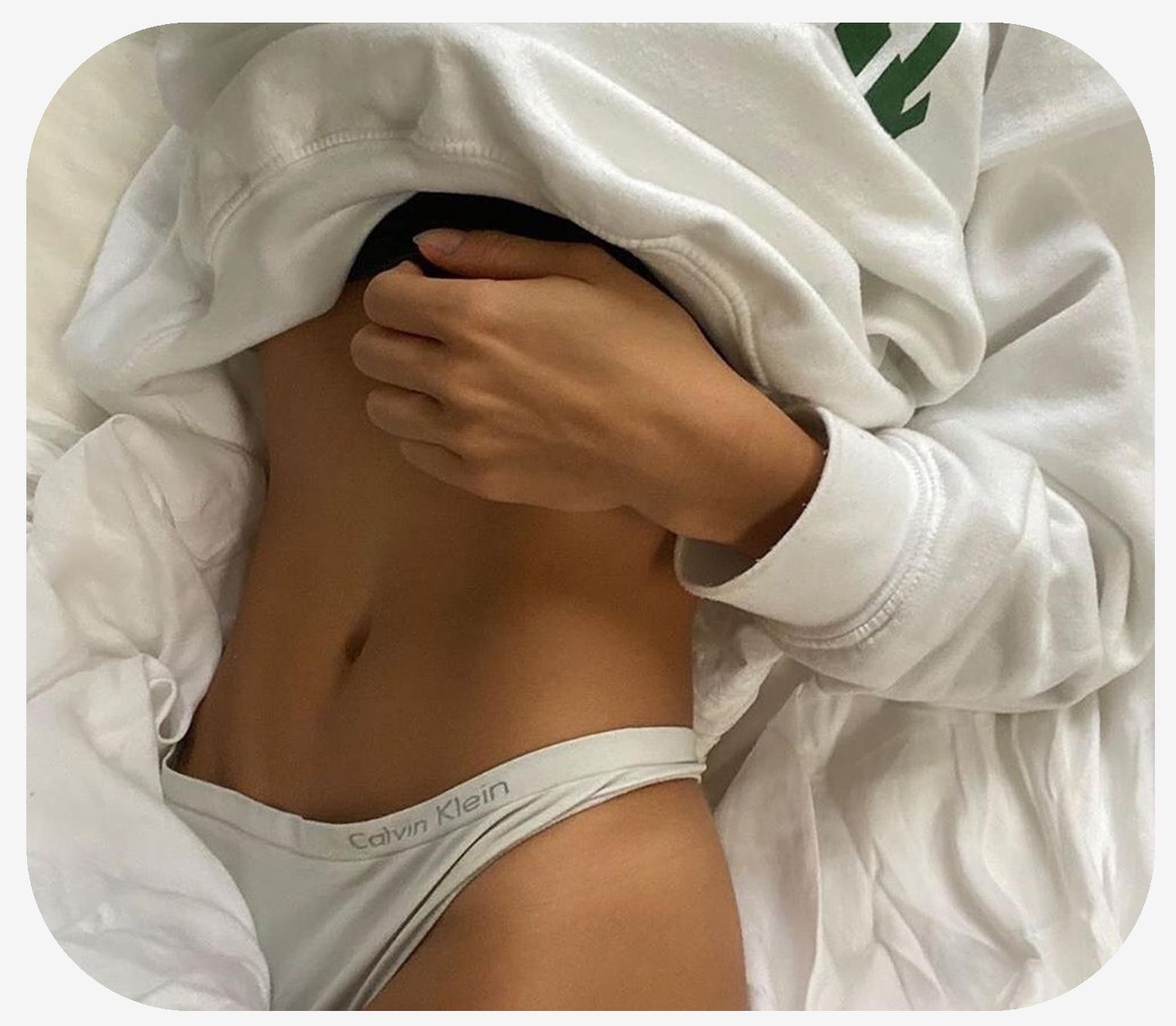 Female laying in bed with her lower body under the covers