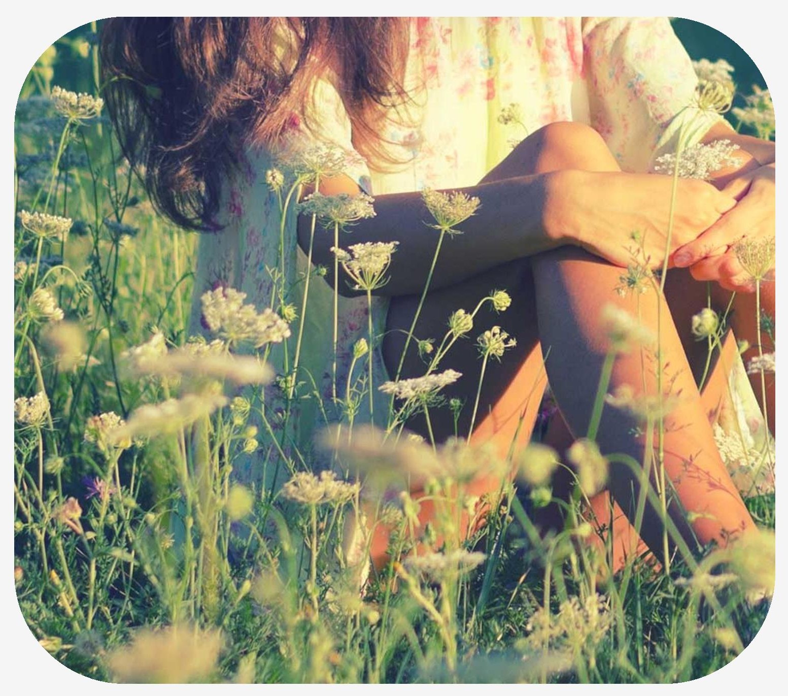 Woman sitting in a tall field of flowers and grass
