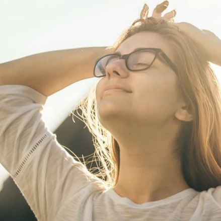 Woman outside taking a deep breath with her hands on her head