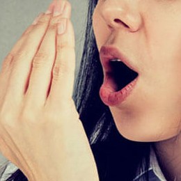Woman breathing on her hadn to check if she has bad breath