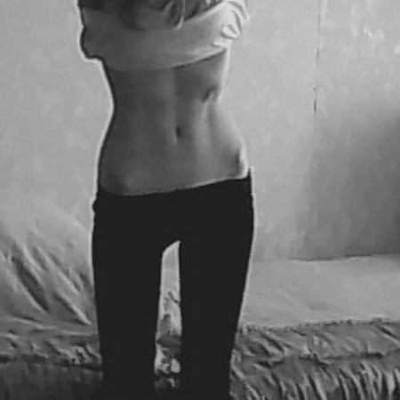 Front view of woman with visable hips standing with hands held in the air.