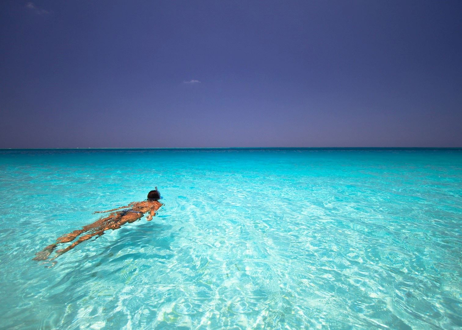 Woman swimming in clear blue water with a snorkel