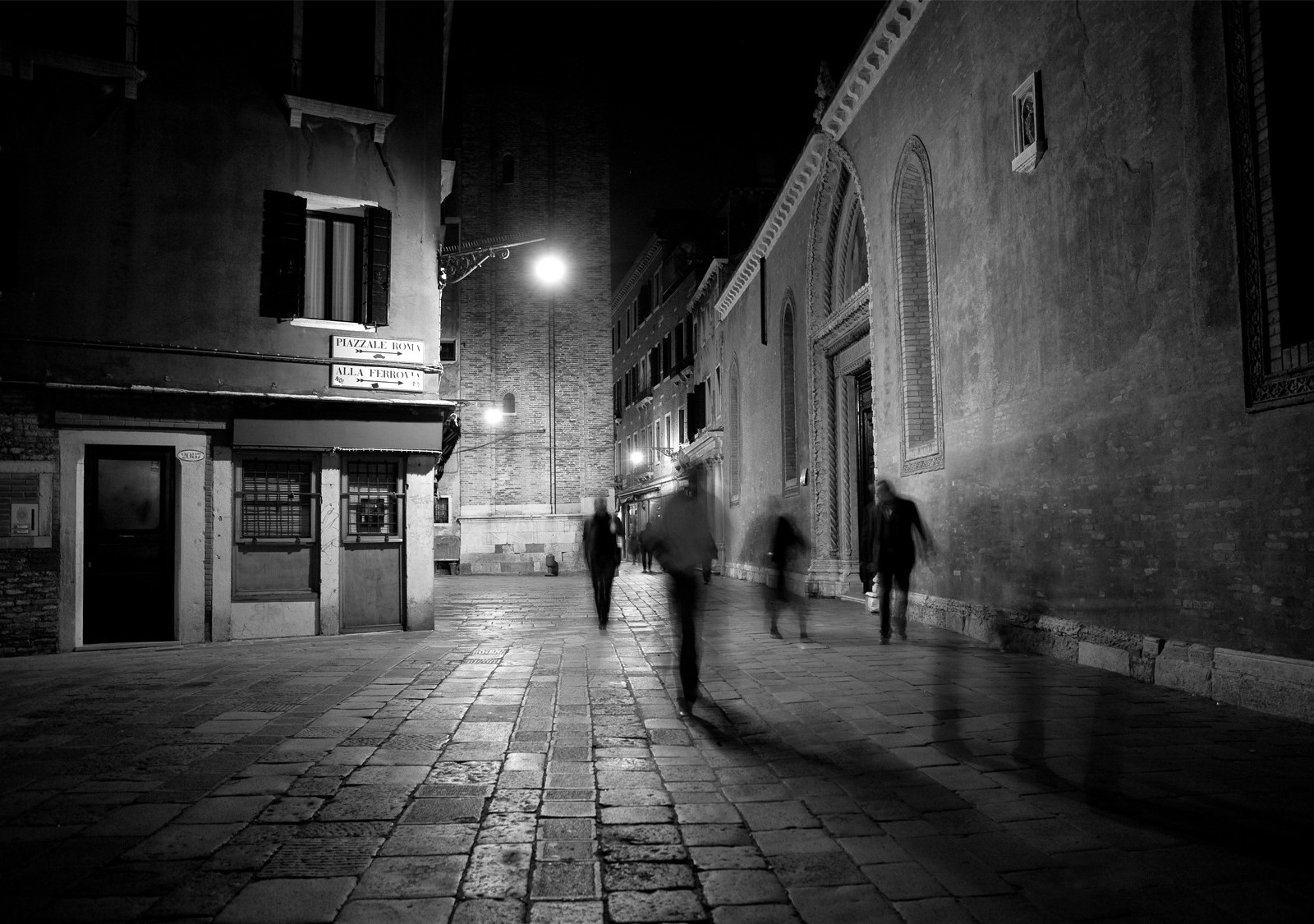 A European walkway at night with people walking