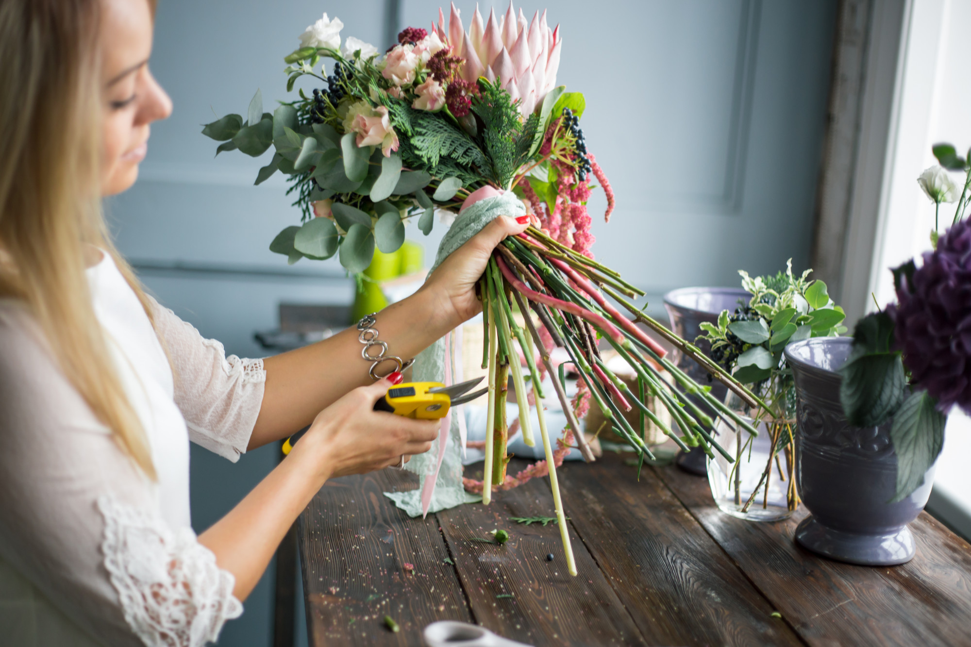 Woman clipping the bottom of a flower arrangement with plant cutters