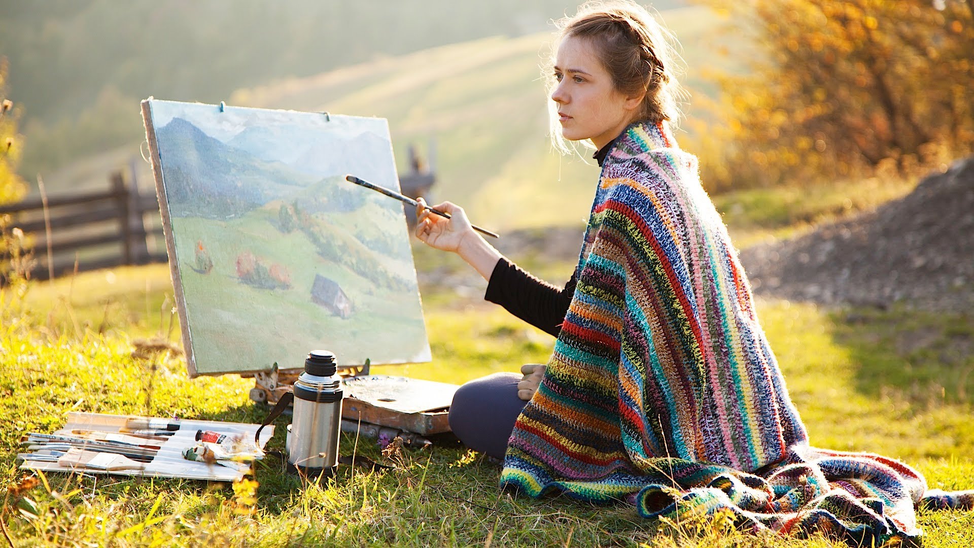 Woman sitting down painting ouside